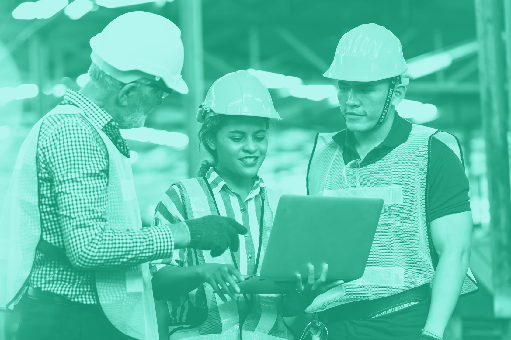 Three workers in safety gear review a laptop together inside a facility within the Louisiana chemical industry.